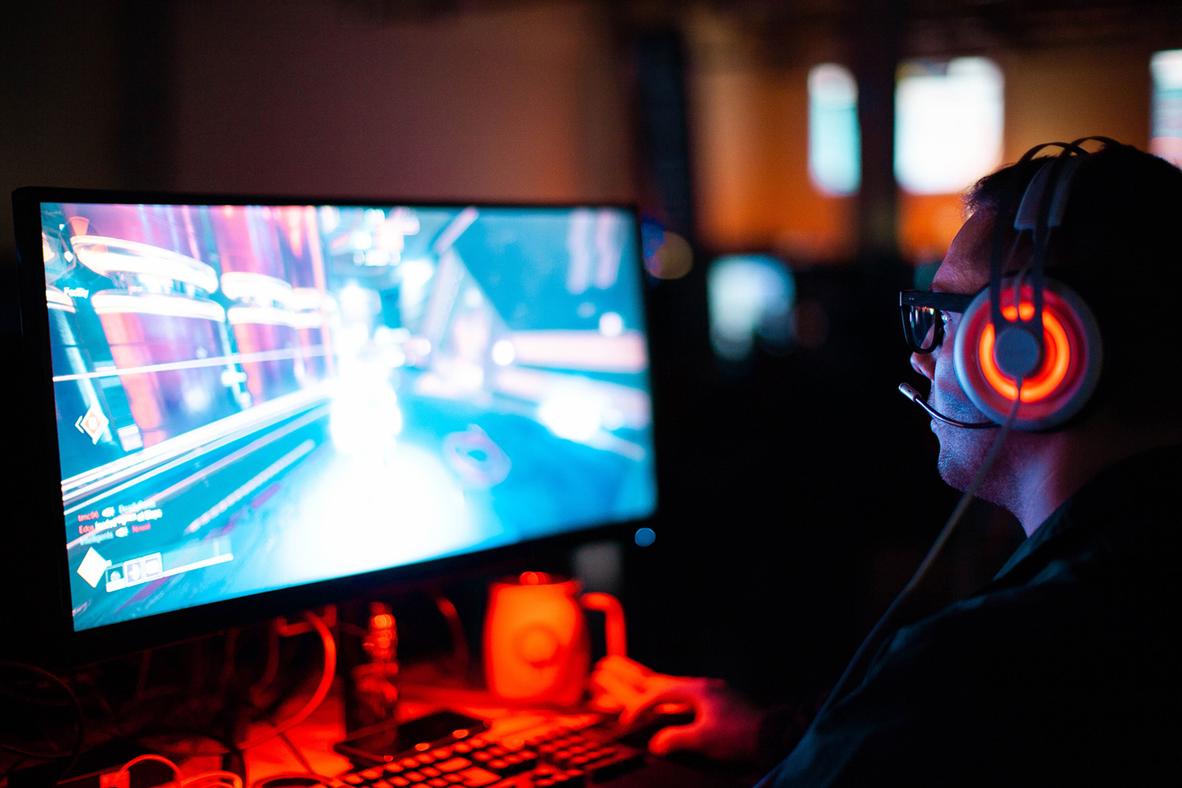 Gamer jugando en un ordenador con auriculares a un FPS